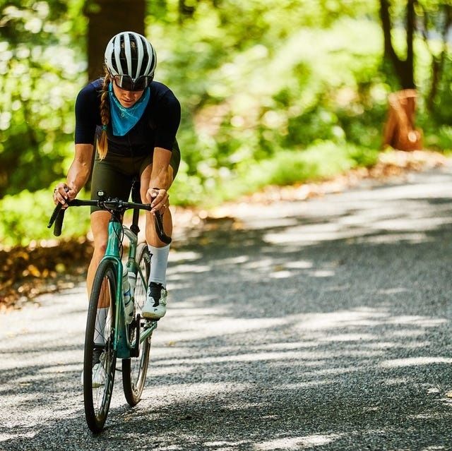 Ciclista consulta su bicicleta mientras pedalea por una carretera arbolada