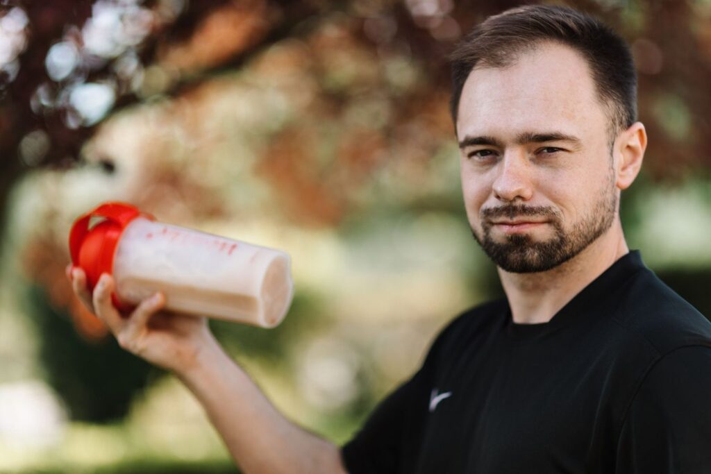 Ciclista sostiene un batido de recuperación en un entorno natural